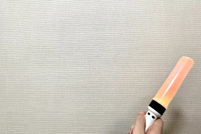 オレンジ色に光るペンライトを持つ手元